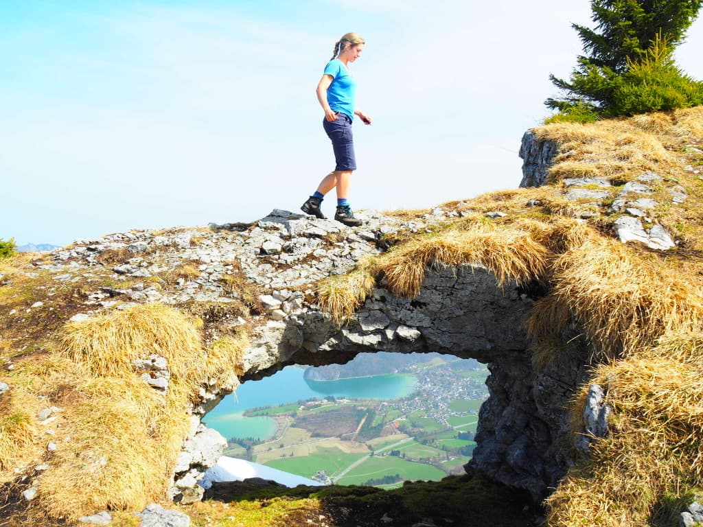 Natasha standing on a rock arch high above a lake