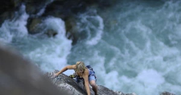 Climbing on rocks beside rushing river rapids